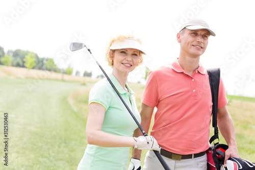 Smiling male and female friends standing at golf course