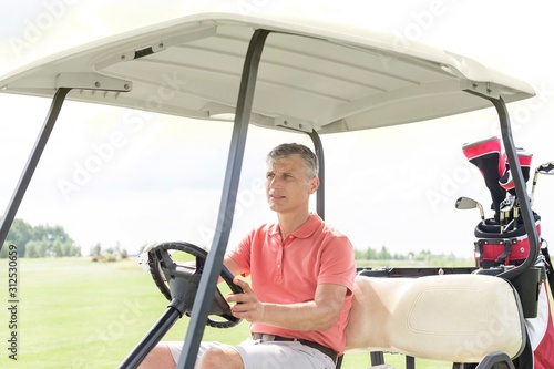 Middle-aged man driving cart at golf course