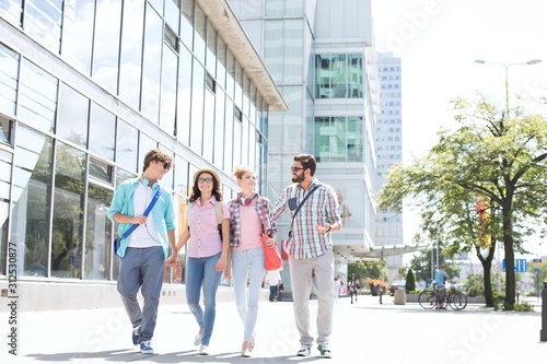 Full-length male and female friends walking on city street