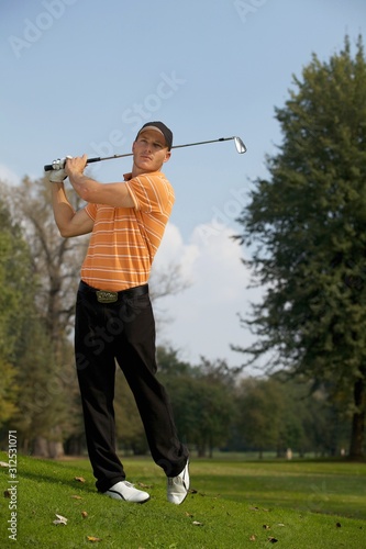 Young man swinging golf club