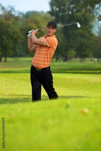 Young man swinging golf club