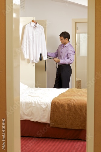 Young man holding tie in hotel room © moodboard