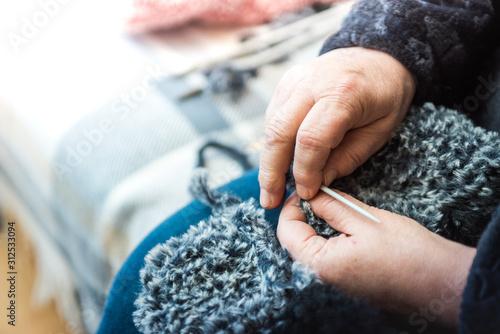 Close up photography of a knitting needle. Woman hands knitting a scarf.