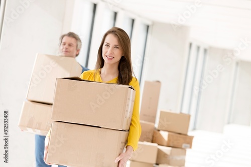 Young businesswoman with male colleague carrying cardboard boxes in new office © moodboard
