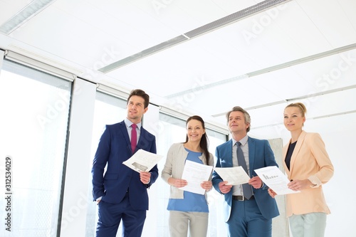 Business people holding documents while looking away in new office