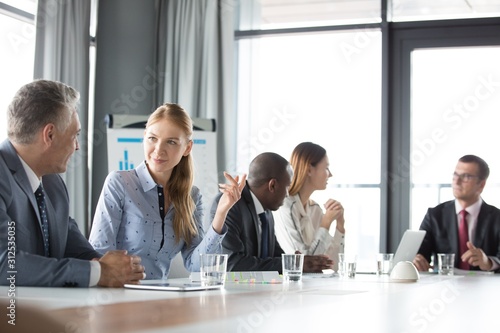 Young businesswoman discussing with male colleague in board room