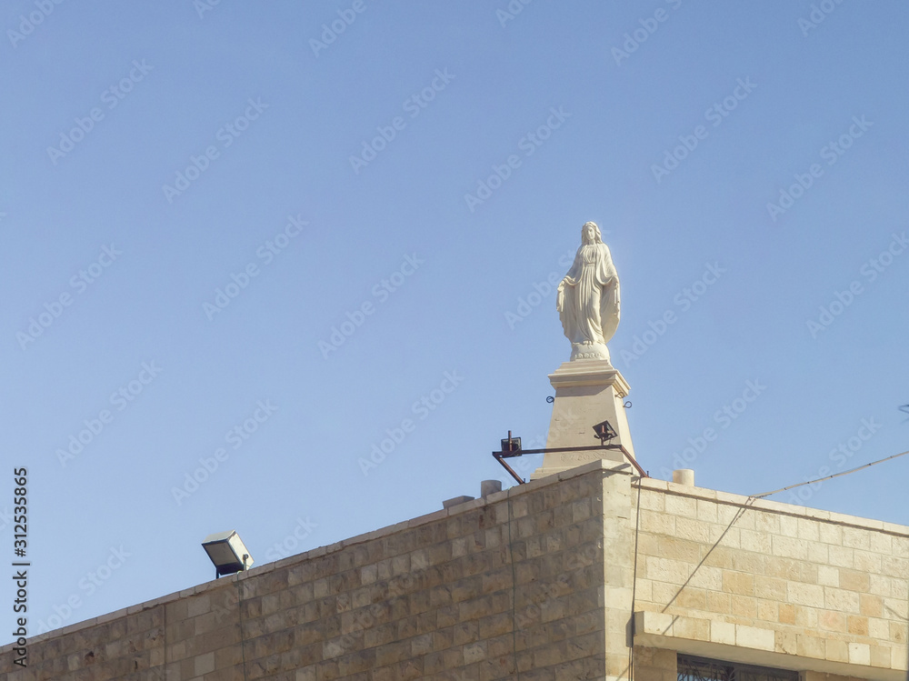 Obraz premium A statue of the Virgin Mary made of white marble stands on the roof of the building in Bayt Sahour, a suburb of Bethlehem. in Palestine