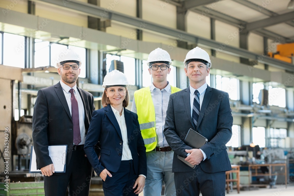 Portrait of confident business people wearing hardhats in metal industry Portrait of confident business people wearing hardhats in metal industry