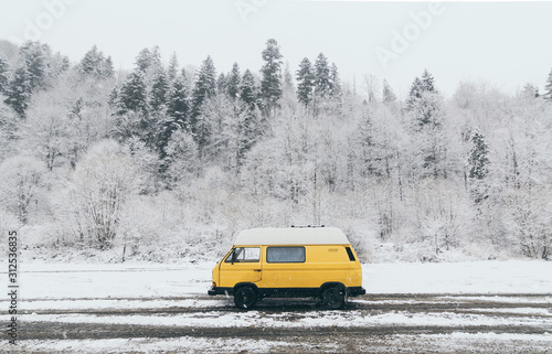Carpathians, Ukraine - December 2019: yellow camper van with winter forest on background