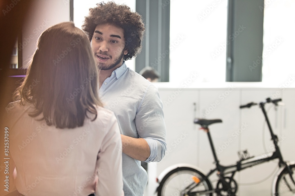 Young businessman talking with female colleague in office Young businessman talking with female colleague in office