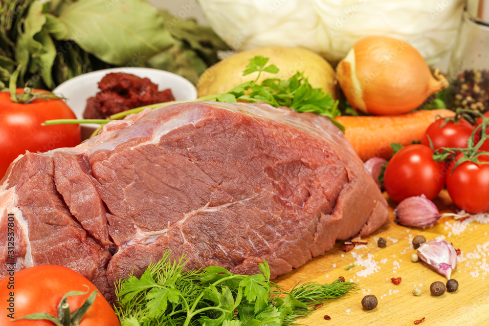 A large piece of raw pork, vegetables and spices for cooking a traditional Russian dish - borsch A large piece of raw pork, vegetables and spices for cooking a traditional Russian dish - borsch