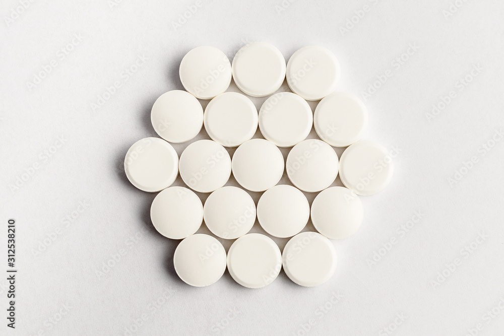 Close up of a group of white pills on white background, beautifully arranged as a hexagon, top view or flat lay Close up of a group of white pills on white background, beautifully arranged as a hexagon, top view or flat lay