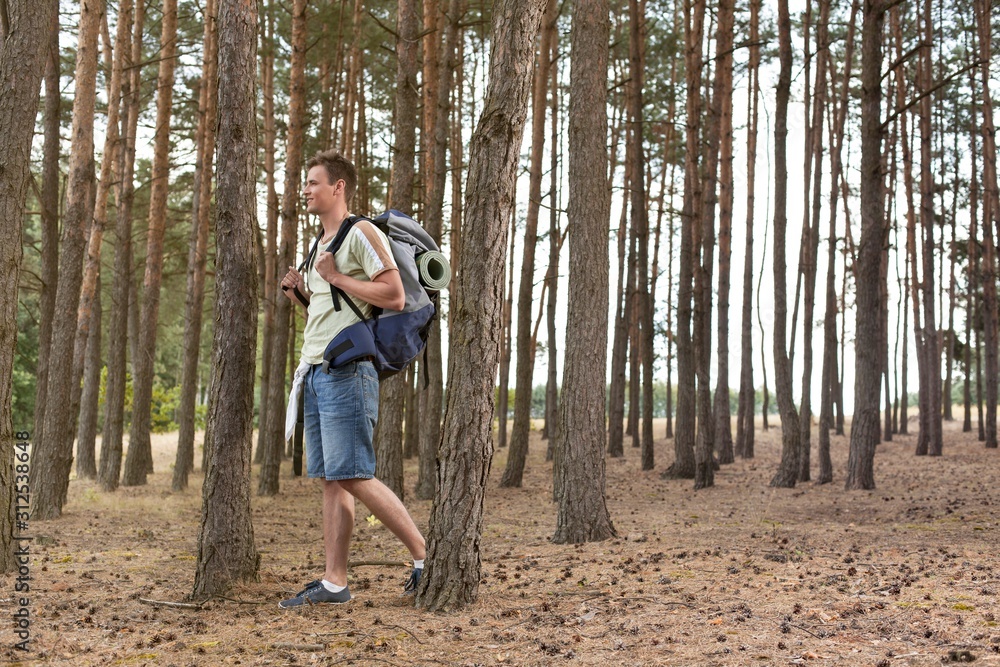 Full length of male backpacker trekking in forest Full length of male backpacker trekking in forest