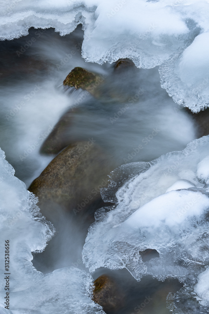 Winter landscape of Boulder Creek captured with motion blur and framed by ice, Rocky Mountains, Colorado, USA Winter landscape of Boulder Creek captured with motion blur and framed by ice, Rocky Mountains, Colorado, USA