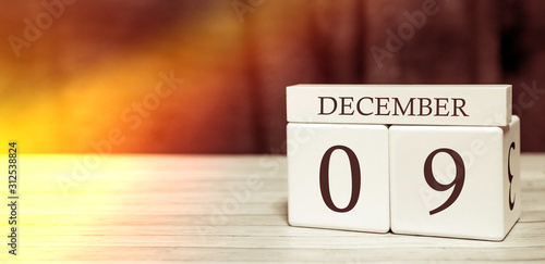 Calendar reminder event concept. Wooden cubes with numbers and month on December 9 with sunlight.