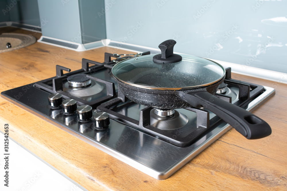 Modern stainless steel gas stove oven in a home with various cookware Modern stainless steel gas stove oven in a home with various cookware