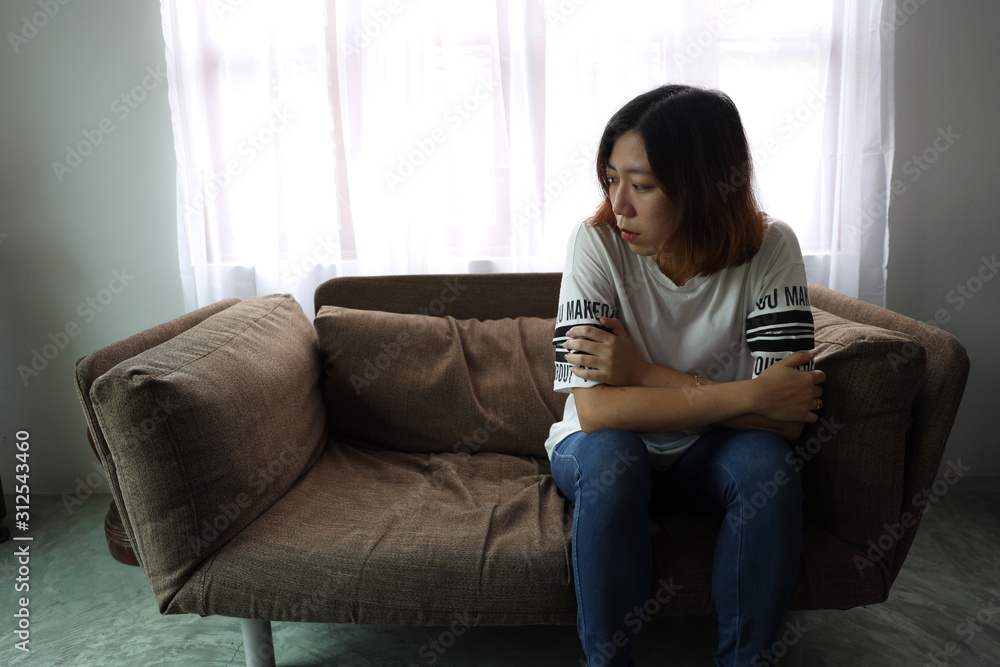 Asian woman stressful face with her hands cover of face. Short hair asian Woman feel lonely and sad sit alone on sofa bed in the living room Asian woman stressful face with her hands cover of face. Short hair asian Woman feel lonely and sad sit alone on sofa bed in the living room