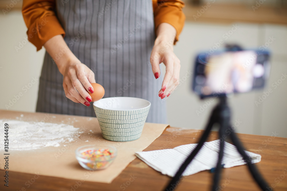 Cropped portrait of unrecognizable young woman breaking eggs while filming baking tutorial for video channel, copy space - obrazy, fototapety, plakaty 