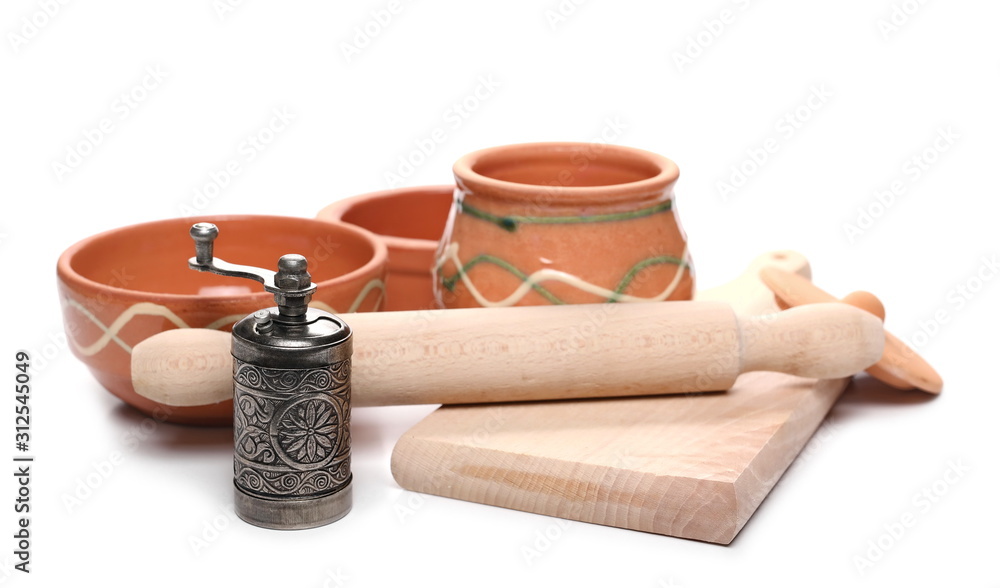 Empty clay food bowls with wooden chopping board and pepper mill isolated on white background
