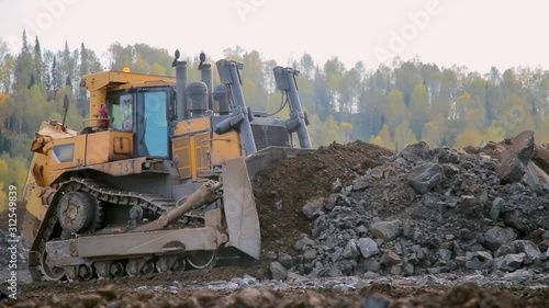 Yellow tracked bulldozer moves your bucket stones