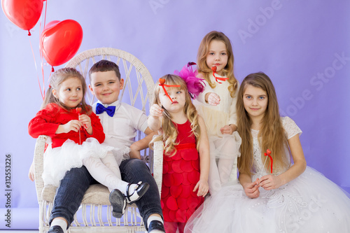 Beautiful kids friends with red balloons in the shape of a heart at the holiday