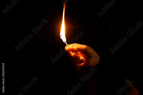 mano sujetando una cerilla encendida sobre fondo oscuro negro  IMG_4943-as19 photo
