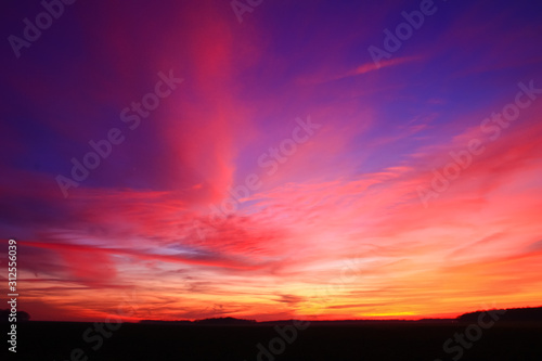 Very colorful clouds in dramatic sky. Romantic sunset at the countryside.