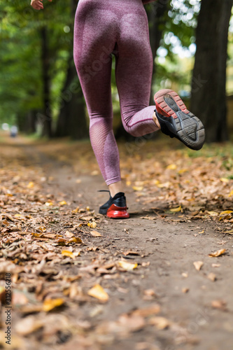 Close up of feet of runner running in autumn leaves training exercise