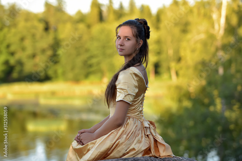 beautiful young princess brunette in a golden dress in the park photo