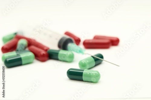 Green capsules red capsules and a syringe isolated