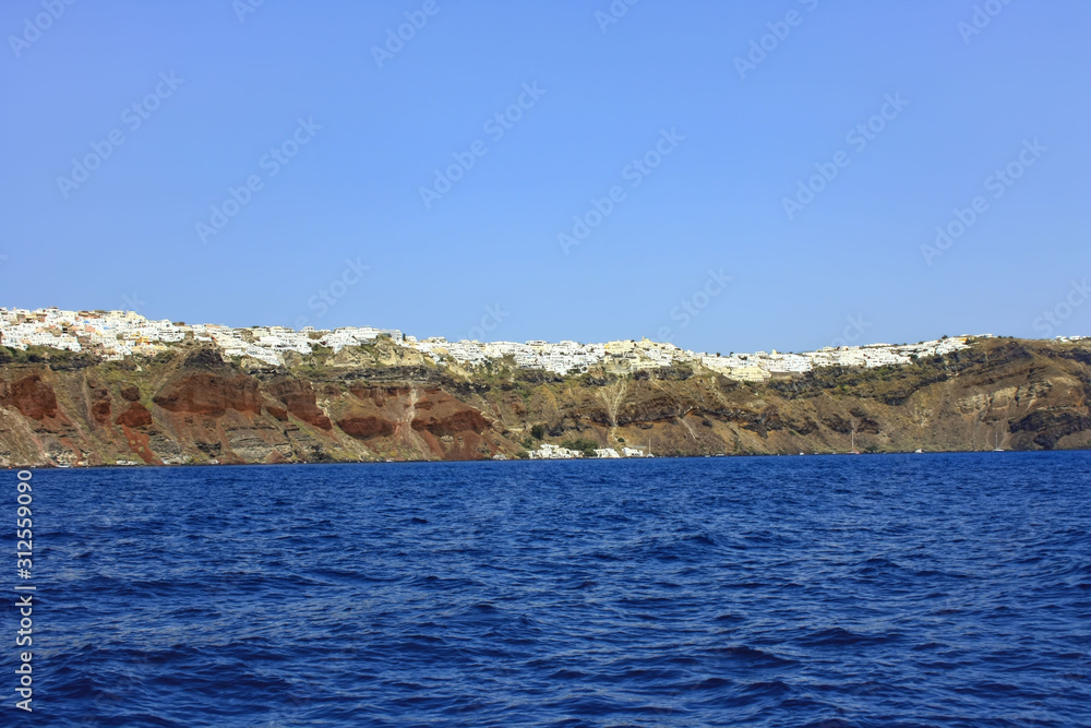 Wybrzeża greckiej wyspy Santorini z usytuowanymi na klifach miasteczkami Wybrzeża greckiej wyspy Santorini z usytuowanymi na klifach miasteczkami