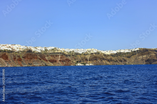 Wybrzeża greckiej wyspy Santorini z usytuowanymi na klifach miasteczkami #312559090