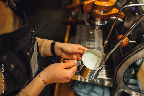 Close up view Barista steaming milk in metal pitcher. Barista making coffee.