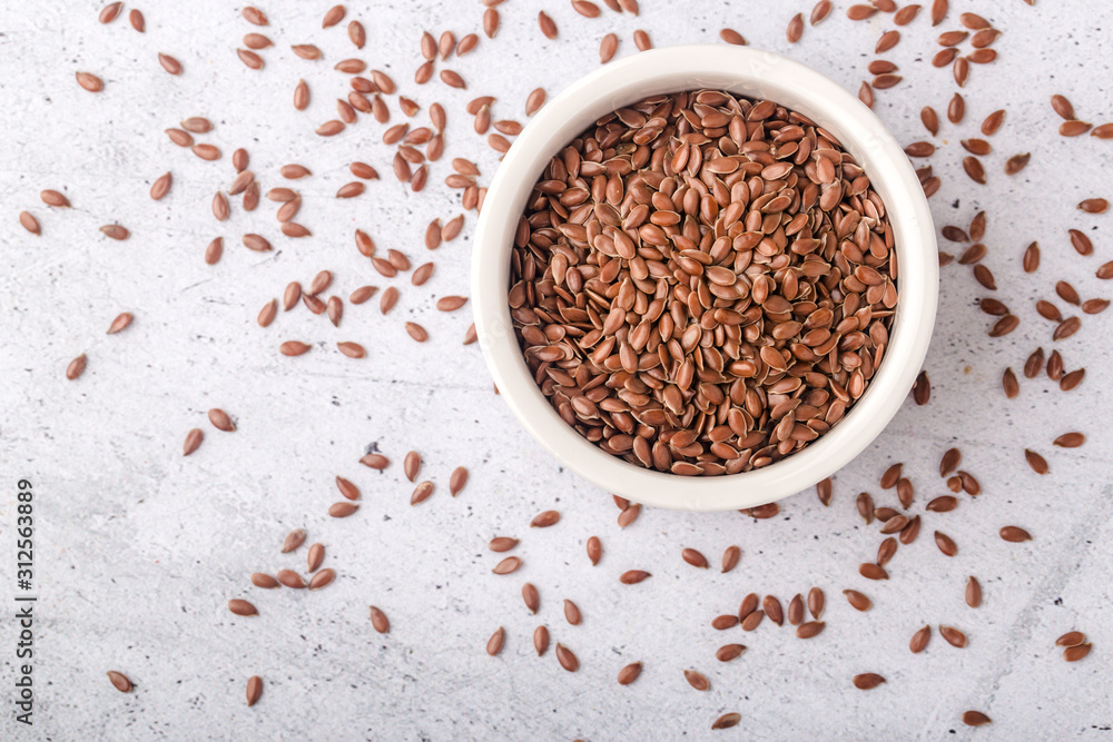 Brown flax in a white bowl on a gray background Brown flax in a white bowl on a gray background