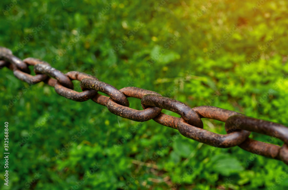 Old rusty chain hanging over green grass background Old rusty chain hanging over green grass background