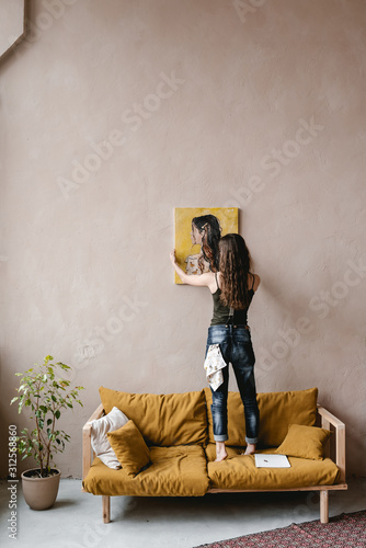 Anonymous painter hanging portrait on wall