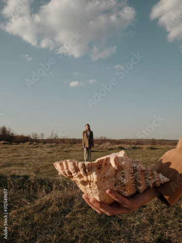Young man holding woman in seashell in field