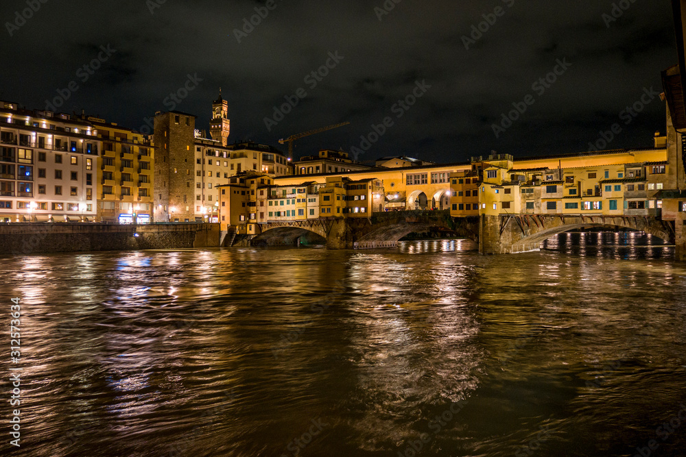 Vista nocturna del río Arno y el Ponte Vecchio en la ciudad medioeval y cuna del Renacimiento de Florencia, Italia.