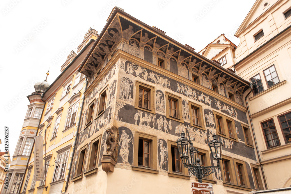 The architecture of the old city of Prague. The ancient building is painted with figures of people.