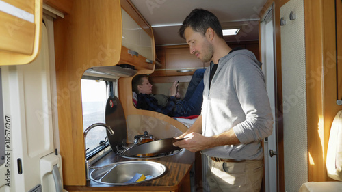 A man washes dishes in a motorhome. car travel concept