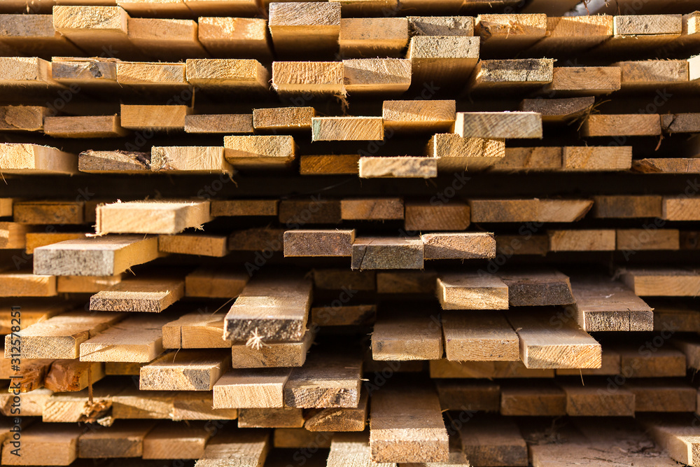 Stacked lumber background. Folded wood. Close-up cross section of board. boards stick out from pile of lumber. Lumber for use in construction. Stacked lumber background. Folded wood. Close-up cross section of board. boards stick out from pile of lumber. Lumber for use in construction.