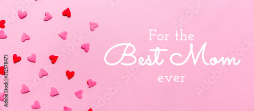 For the Best Mom ever wording and two tone heart sprinkles on the solid pink background. Romance, love, Valentines and mother's day concept. Flat lay, horizontal wide screen banner format