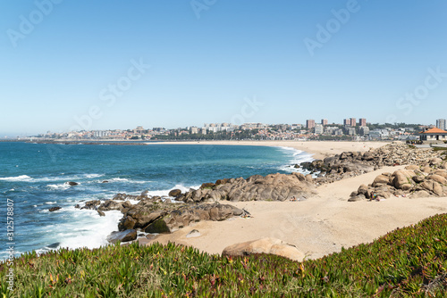 Beautiful view of a sandy beach with granite rocks and Porto at the background. Portugal landscape.