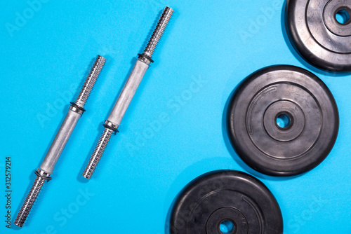 Fitness or bodybuilding. Sports equipment on a blue background, barbell, dumbbell, top view