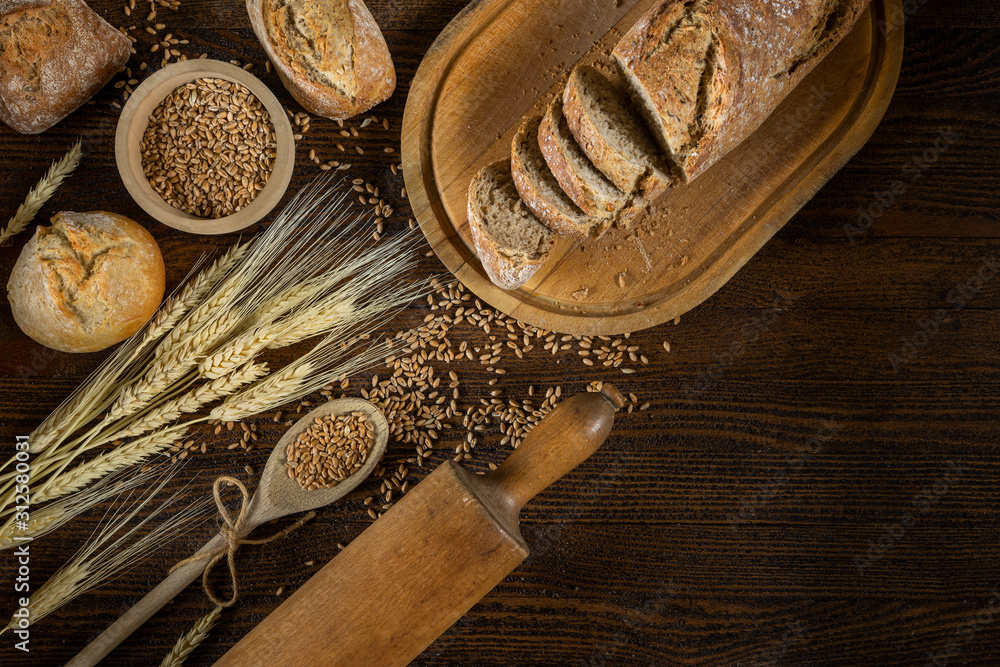 Bread, traditional bread and wheat on wooden backround.