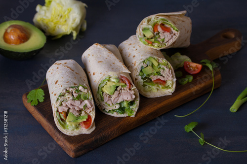 Chicken wraps with avocado, tomatoes and iceberg lettuce. Tortilla, burritos, sandwiches, twisted rolls