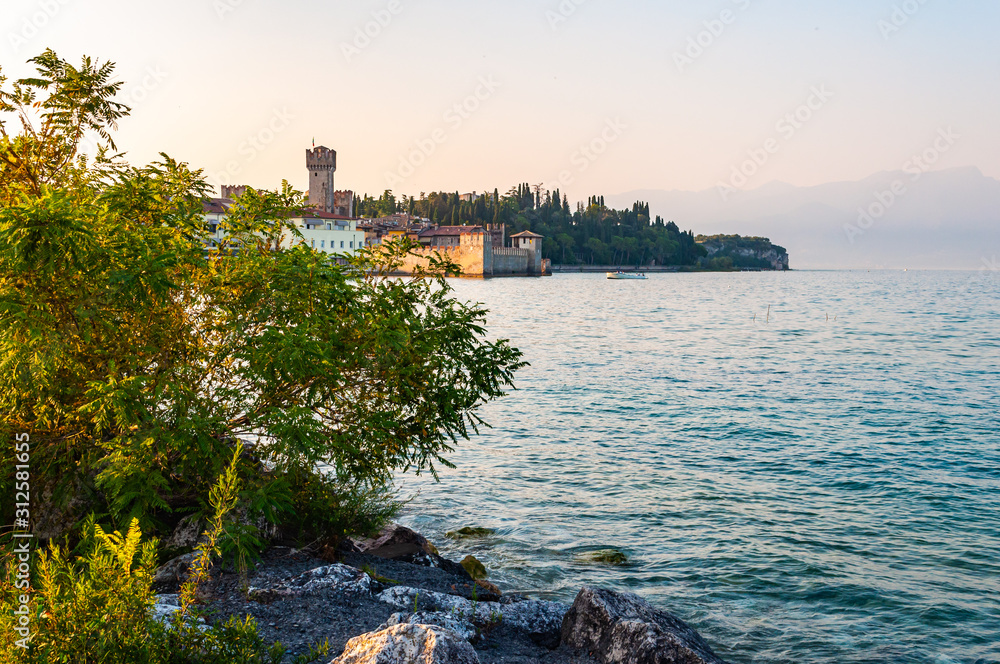 Evening cityscape of Sirmione medieval city located on southern peninsula of Garda lake in Lombardy, Italy. Waterscape scene