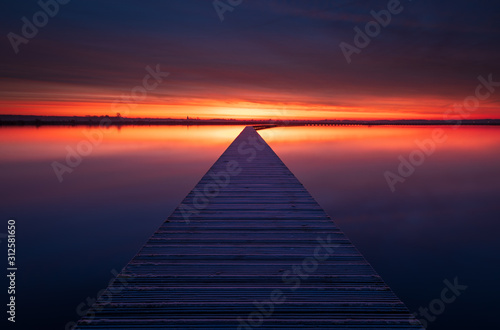 Very colorful and tranquil dawn at a jetty in a lake. Groningen, Holland.