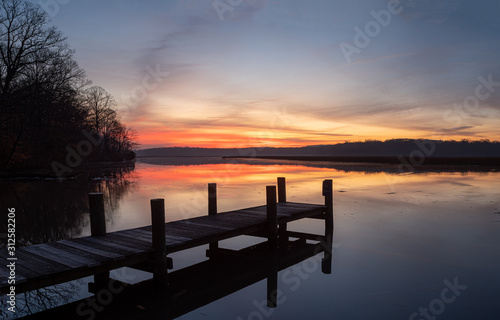 Dock on a River Shore with Colorful Dawn Sky and Calm Water with Reflections