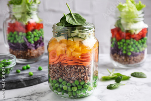 Healthy salads in glass jars on marble table